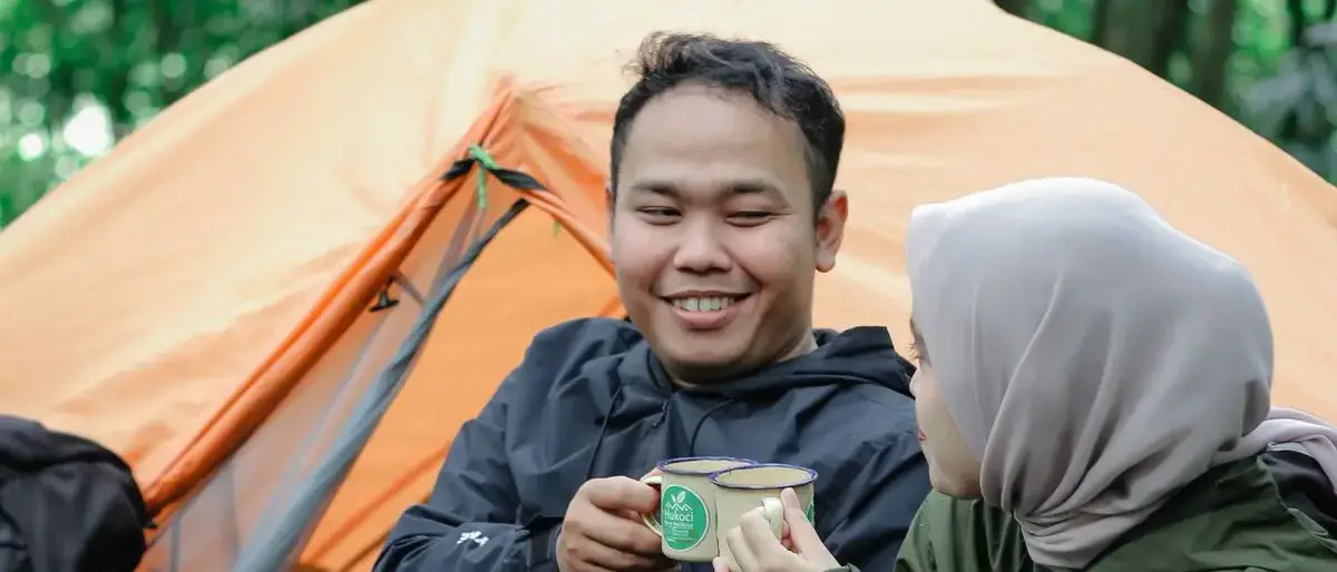 Stel drinkt koffie voor hun tent in het bos